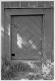 Panelklädd bräddörr på en f.d. handelsbod från 1700-talet. Dörren är klädd med profilerade bräder som bildar ett diagonalt rutmönster. Månstad Se även färgbild MÅN 0020.