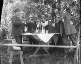 Sju okända herrar med höjda glas.