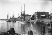 Skutor liggandes i G:a hamnkanalen. Närmast i bild ligger en galeas med sina typiska höga riggar lastad med virke. Längre bort syns även en s.k. älvbåt. Strömmerska huset till höger.
Foto fr. sent 1910-tal.