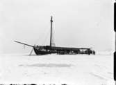 Förlist skuta i isen utanför Vänersborg. Sannolikt är detta skonaren Concordia som gick på Normansgrundet 23/10 1921.
Concordia lär ha legat kvar på grundet över vintern, och vänersborgarna gjorde utflykter till den förlista skutan. På fotografiet ses runt 25 personer runt haveristen.
