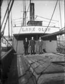 Lastångaren Lars Olof i Vänersborgs hamn. Tre män står på däcket.
