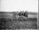 Porträtt av tre herrar med bil. Hunne el. Halleberg i bakgrunden.