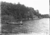 Man, sitter i roddbåt och fiskar.
