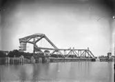 Arbete med järnvägsbron över nya trafikkanalen. Bron blev godkänd i  augusti 1916 och togs i bruk strax därefter.. Bakom bron ligger fortfarande banvallen kvar över kanalen, vilken när bron stod klar muddrades bort. På bron poserar 12 manspersoner.
Järnvägsbron är ritad av en svensk, men konstruktionens upphovsman är Joseph Baermann Strauss, vilken ritat den något mer kända Golden Gate-bron i Kalifornien.