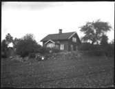 Olof Jonssons text: Simon i Örsbo med familj. Bilden visar det gamla bostadshuset på en av Örsbogårdarna -  idag rivet. Personerna som sitter framför huset okända