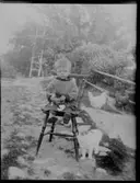 Allan Eriksson, Hjärtum 1913-03-21, med kattunge i knät och intill pinnstolen, där han sitter, står kattmamman. Två hönor finns med på bilden, som är tagen i trädgården i Brevik.