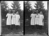 Tre unga flickor vitklädda med svarta strumpor och rosetter i håret