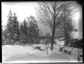 Vintermotiv, bostadshuset med planterade björkar och sågbock. I bakgrunden syns Öresjö och körhuset på nuvarande Brevik 1:33.