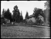 Ladugården med tillbyggnad och bostadshuset på Torpängen. Nils, Hjärtum 1918-01-09, Olga, född Olsson, Forshälla 1891-05-12, Erik, Hjärtum 1919-07-26 med katten i knät, Sven, Hjärtum 1915-05-14.