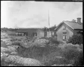 Vy över boningshuset på Arnstorp och den gamla ladugården syns till vänster på bilden. På bilden syns också flaggstången och timret till ny ladugård på Arnstorp som laftats upp innan den skall monteras på sin rätta plats.