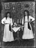 Anna Johansson, Hjärtum 1891-01-05, och hennes syster Gerda Johansson, Hjärtum 1893-10-15, som lucior med kaffebricka och stearinljus inomhus på Torpet (Arnstorp). (På väggen hänger ett inramat diplom Johan Jonsson, Arnstorp.)