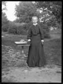 Gerda Johansson, Hjärtum 1893-10-15, som konfirmand intill litet bord i trädgården på Torpet (Arnstorp)