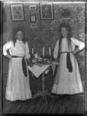 Anna Johansson, Hjärtum 1891-01-05, och hennes syster Gerda Johansson, Hjärtum 1893-10-15, som lucior med kaffebricka och stearinljus inomhus på Torpet (Arnstorp). (På väggen hänger ett inramat diplom Johan Jonsson, Arnstorp.)