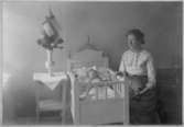 Olga, född Olsson, Forshälla 1891-05-12 med sonen Sven, Hjärtum 1915-05-14, som ligger i spjälsängen