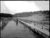 Den översvämmade vägen mellan Sågbron och Nötbron, Fjällvägen vid Fredskogen, där man anordnat särskild gångbana för gående. I vattnet står Erik Jonsson, Hjärtum 1919-07-26.