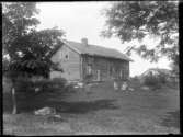 Det gamla boningshuset och ladugården på Torpet (Arnstorp) framför byggnaden sitter Olga Jonsson, född Olsson, Forshälla 1891-05-12 med sonen Sven, Hjärtum 1915-05-14, och Beda Jonsson, född Björn, Bäve 1892-12-20 med sonen John, Hjärtum 1916-12-08