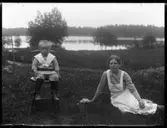 Allan Eriksson, Hjärtum 1913-03-21, Signe Johansson, Hjärtum 1896, sitter nedanför boningshuset i Brevik med Öresjö glittrande i bakgrunden.