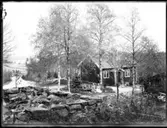 Familjen Jonssons rödmålade bostadshus med vita knutar och tvåkupiga tegelpannor på taket. Sven, Hjärtum 1915-05-14, Nils, Hjärtum 1918-01-09,  Erik, Hjärtum 1919-07-26, Olga, född Olsson, Forshälla 1891-05-12 och Olofs syster Jeanna Jonsson, Hjärtum 1874-04-03. I bakgrunden syns Öresjö och vägen mellan Sågbron och Nötbron, Fjällvägen med sina stengardister. Vid sidan av huset ligger tegelrör till dränering.