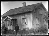 Anders Andersson, Forshälla 1888-10-13, stående framför det ännu omålade bostadshuset