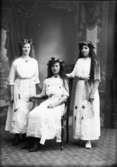 Edit Ekstedt  Vänersborg
Ateljébild där tre flickaor är klädd till brudar/tärnor. Alla klädda i vita klänningar med påsydda, konstgjorda blommor. Atta är försedda med krans.