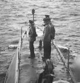 Militärer står i stationer för förtöjning ombord på U-båten Hajen.
