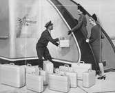 Två kvinnor går in i ett flygplan, man räcker upp en resväska. Douglas Aircraft.