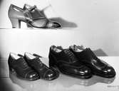 Tre par skor i skinn. Skor längst upp med t-slejf och klack, skor i Oxfordmodell på nedre hyllan.
