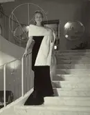 Nordiska Kompaniet. Kvinna i mörk aftonklänning och vit minkstola.