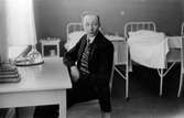 Fotograf Gustav Andersson sitter vid bordet i en sjuksal på sanatoriet i Eksjö, där han behandlades för tuberkulos åren 1921-1922.