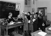 Spardag i Sverkerskolan, Uppsala, oktober 1944. Flickorna köar för att lämna sina slantar till läraren Ester Andersson
