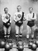Atletklubben Thule, Trelleborg år 1898. Tre kraftkarlar klädda i trikåer. Tyngder ligger framför dem. Från vänster A K Jäger, A Lindsjö och Rasmus Olsson.
A K Jäger hade en livsmedelsbutik i hörnan Lejonhjälmsgränden/Norregatan. Denna hörna kallades 