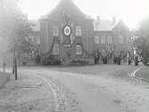 Tegelbyggnad med dekorationer. Sjukhus. 50 års jubileum. På dekorationen står: 1863-1913 och monogrammet CP. Det är överläkare Constantin Perssons 50-årsdag som firas.
