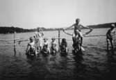 Vuxna och barn badar tillsammans, troligtvis i Tulebosjön cirka 1930.