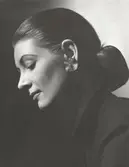 Nordiska Kompaniet. Porträtt av modell i stram frisyr med låg hårknut och stort örhänge. Text på baksidan: 