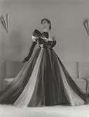 Modell i flerfärgad balklänning i tyll med stor rosett och operahandskar.
