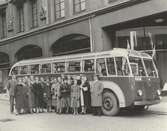 En samling tonåringar och två män vid en buss utanför Nordiska Kompaniet i Stockholm.