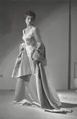 Modell i hellång aftonklänning i siden, sjal och pärlhalsband. Från Balenciaga.