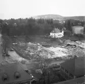 Wargöns AB. Byggnation av PM 5 1959-60. Foto och påförd  text av dåvarande ritkontorschefen Ragnar Söderberg.

Första stora sprängskottet har gått för det nya pappersbruket i Vargön den 17/4 1959.

Jättegrytor som sprängdes bort. Gösta Svensson och hembygdsföreningens ordf. Karl-Johan Höglund medverkade till att de som finns bevarade utanför PM 5 räddades undan de övrigas öde som blev tippen på Kasengärdet. Efter sprängningen var märkligt nog de flesta oskadade. Troligen var antalet grytor 9 st.