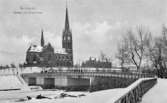 Vinterbild med Storbron i förgrunden. Till vänster Gustav Adolfskyrkan och till höger Flickskolan. Text på vykortet 