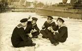 Fyra sjömän spelar kort framför torpedbåt No.12.