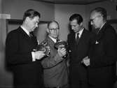 Intendent Nils Ålenius och tre andra män besiktigar silverföremål, sannolikt vid invigning av silverutställning hos Uppsala Fabriks- och hantverksförening, Nedre Slottsgatan, Uppsala 1944
