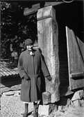 Kvinna vid portliderstolpe, Uppland sent 1920-tal eller 1930-tal