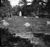 Domarering invid provhögarna på Hols gärde. Stenen i bakgrunden är en bautasten.