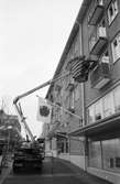 Uppsättning av blomlådor på hus vid Mölndals Torg med hjälp av kranbil, år 1985.

Fotografi taget av Harry Moum, HUM, Mölndals-Posten.