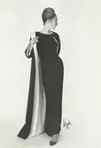 Mannekäng i aftonklänning i svart cloqué med tillhörande svart och vit kappa, håret uppsatt i svinrygg. NK:s Franska damskrädderi efter original från Hubert de Givenchy.