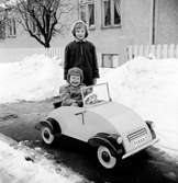 Tom Andersson i lådbilen en vinterdag på Odengatan 22 i Huskvarna. Bakom honom står flickan Nelson.