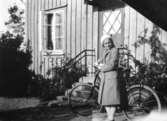 Rosa Pettersson (född Krantz) står vid sin nya cykel, troligtvis 1932. Hon står utanför personalbostaden på Stretered.