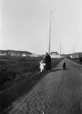 Margit Hellström och ett barn promenerar längs Kungsbackavägen (idag: Gamla Kungsbackavägen), okänt årtal.