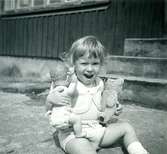 Sommaren 1955. Veronika med liten babydocka och nalle som har hållit sig fin. Sparkbyxa och bolero stickad av Birgit i tunt bomullsgarn