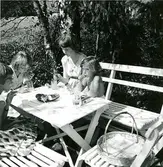 Saft i bersån, nu igenvuxen. Britta Molin, Ann Madgård, Karin Molin som var barnkär och skulle lära sig sällskapsdans. Obs. slät kardemummakrans från bageriet på bordet. Mormor köpte alltid det. Birgit och Gunnel fortsatte traditionen. Jag föredrog bulle med socker och gul kräm. Getingar samlades i bageriet och i vår berså.
